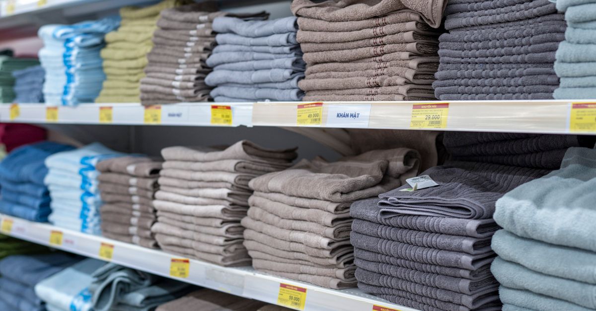 Regal mit gestapelten, gefalteten Frottee-Handtüchern in gedeckten Naturtönen wie Beige, Grau und Taupe.