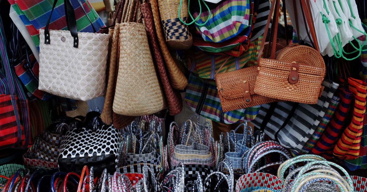 Ein Marktstand mit vielen bunt geflochtenen Körben und Taschen, die als nachhaltige Alternative zu Plastiktüten hängen und stehen.