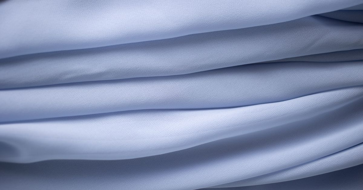 Nahaufnahme von glatt gefalteten, hellblauen Stofflagen mit sanften, gleichmäßigen Wellen.