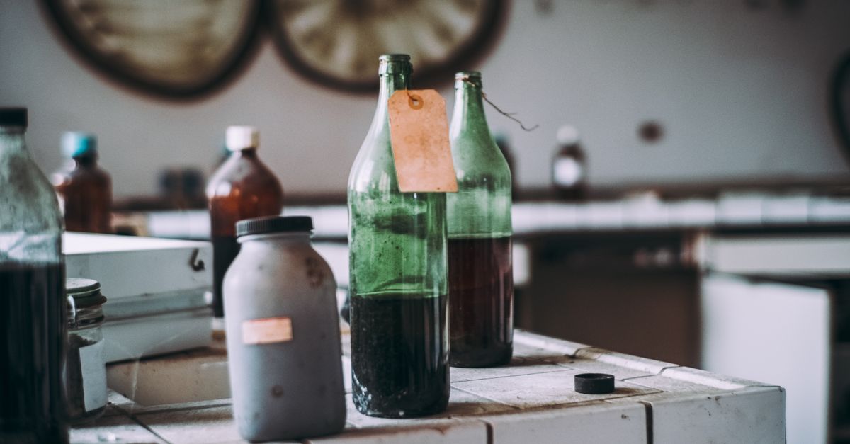 Eine grüne Glasflasche mit teilweise abgelöstem Papieretikett und sichtbaren Kleberresten steht auf einem Tisch.