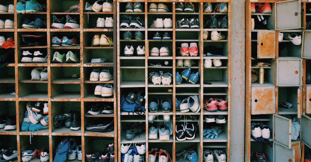 Ein altes Regal mit vielen offenen Fächern, gefüllt mit zahlreichen Paaren Sneakers in unterschiedlichen Farben.