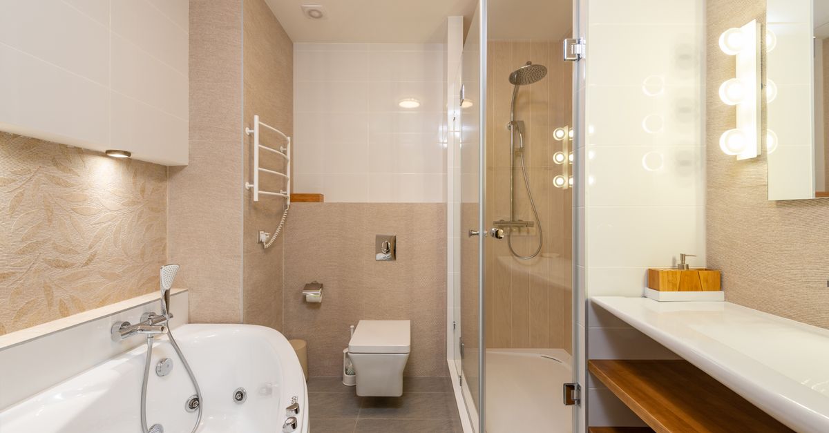 Modernes Badezimmer mit begehbarer Glasdusche, Regendusche und Handbrause vor beigen Fliesen.