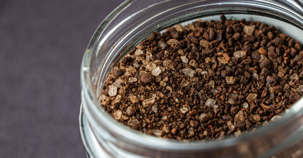 Nahaufnahme eines Glasbehälters mit grob gemahlenem Kaffee, von oben fotografiert.