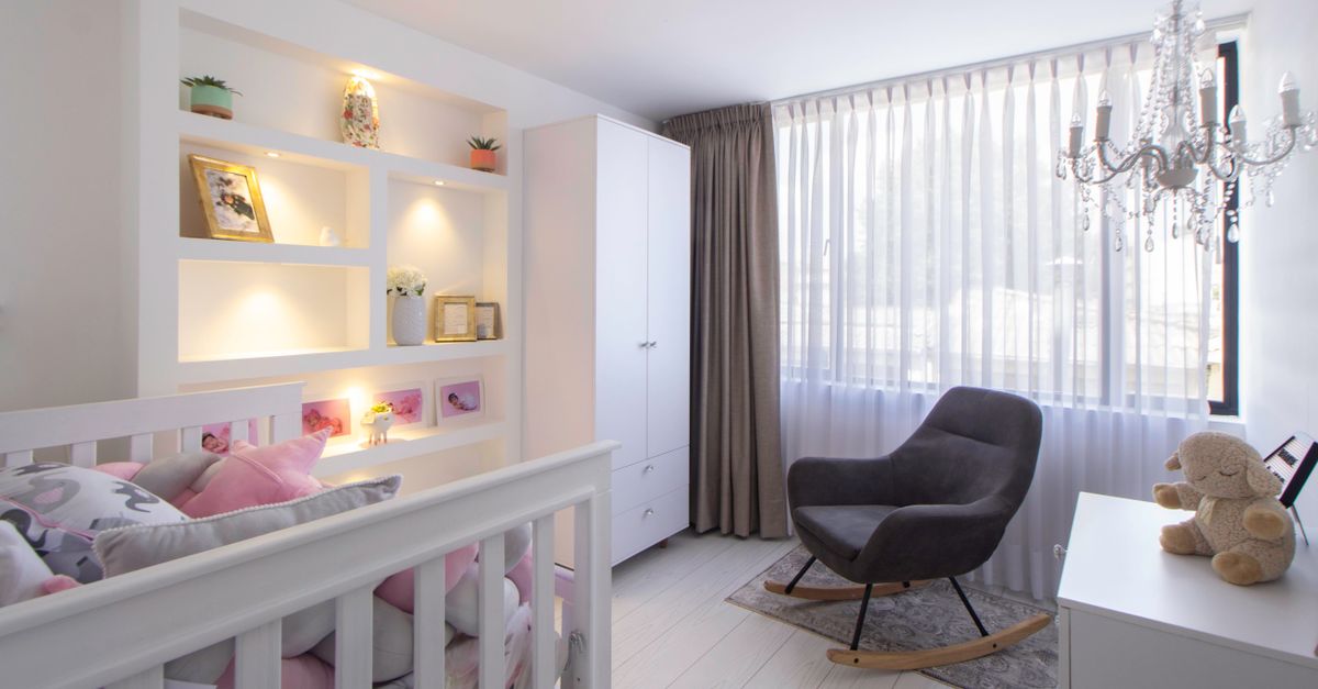 Kinderzimmer mit weißen, in die Wand eingelassenen Regalfächern über einem Kinderbett, dekoriert mit Bilderrahmen und Pflanzen.