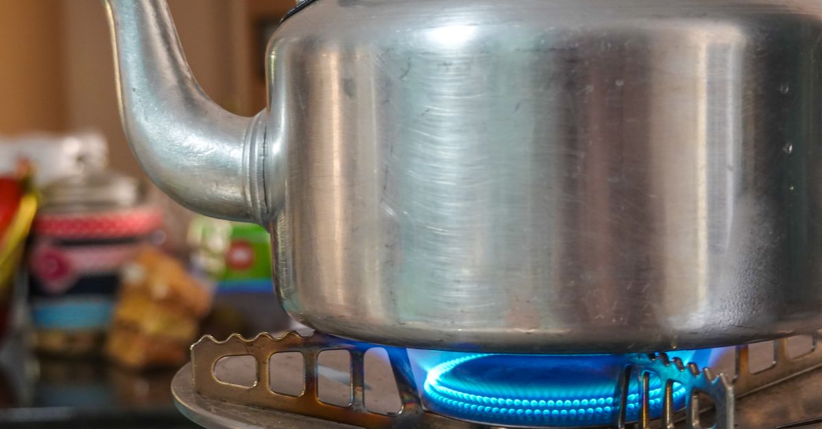 Nahaufnahme eines Metallwasserkessels auf einer Gasflamme auf dem Herd.