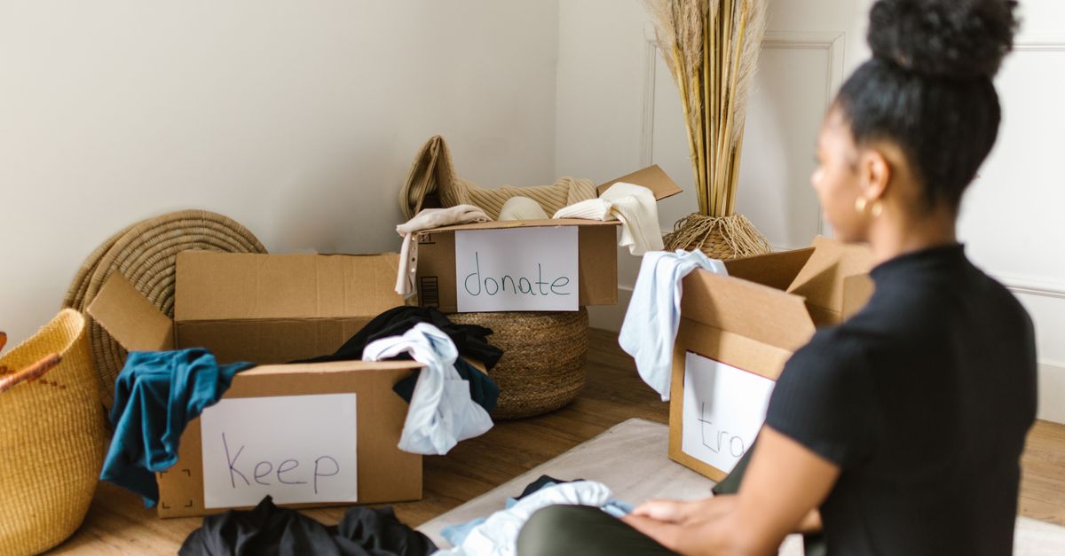 Eine Frau sortiert zu Hause Kleidung in Kartons mit den Aufschriften „Keep“, „Donate“ und „Trash“.