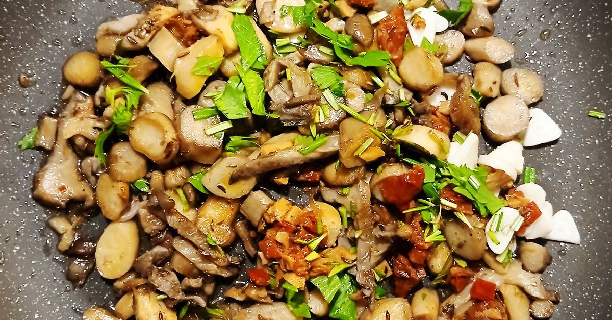 Sautierte Pilze mit Kräutern und Knoblauch in einer Pfanne, von oben fotografiert.