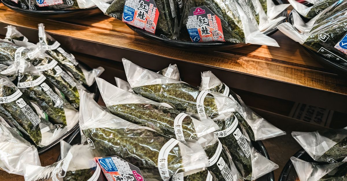 Verpackte Nori-Blätter in versiegelten Plastikbeuteln liegen gestapelt auf einem Holzregal in einem Geschäft.